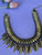 Collar Dorado opaco, unido con hilo negro, cuelgan 12 colmillos mismo color